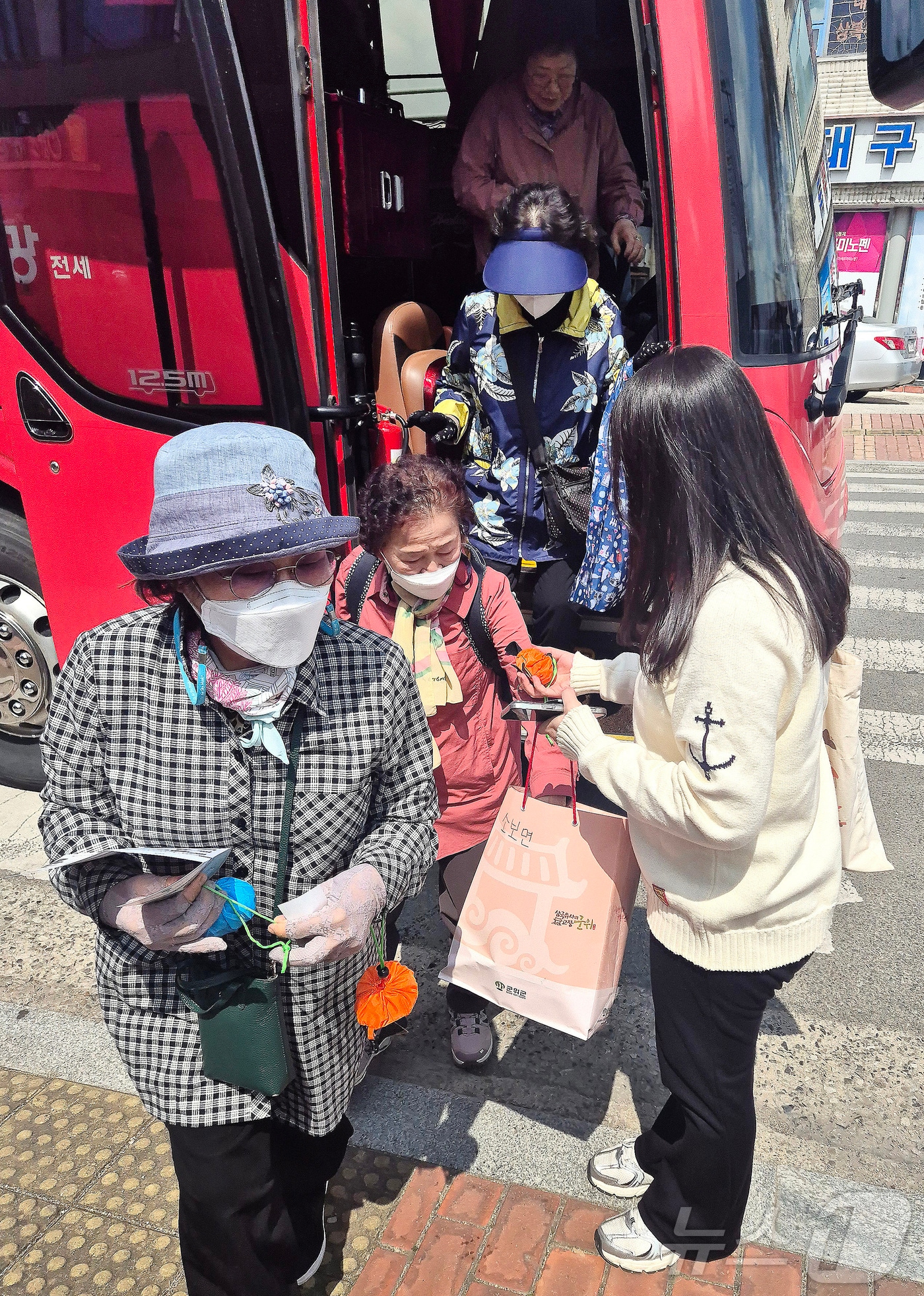 3일 대구시티투어버스를 이용해 군위전통시장을 찾은 관광객이 군위군 관계자가 나눠주는 장바구니와 시장 맛집 리플릿을 받고 있다. (군위군 제공우ㅣ