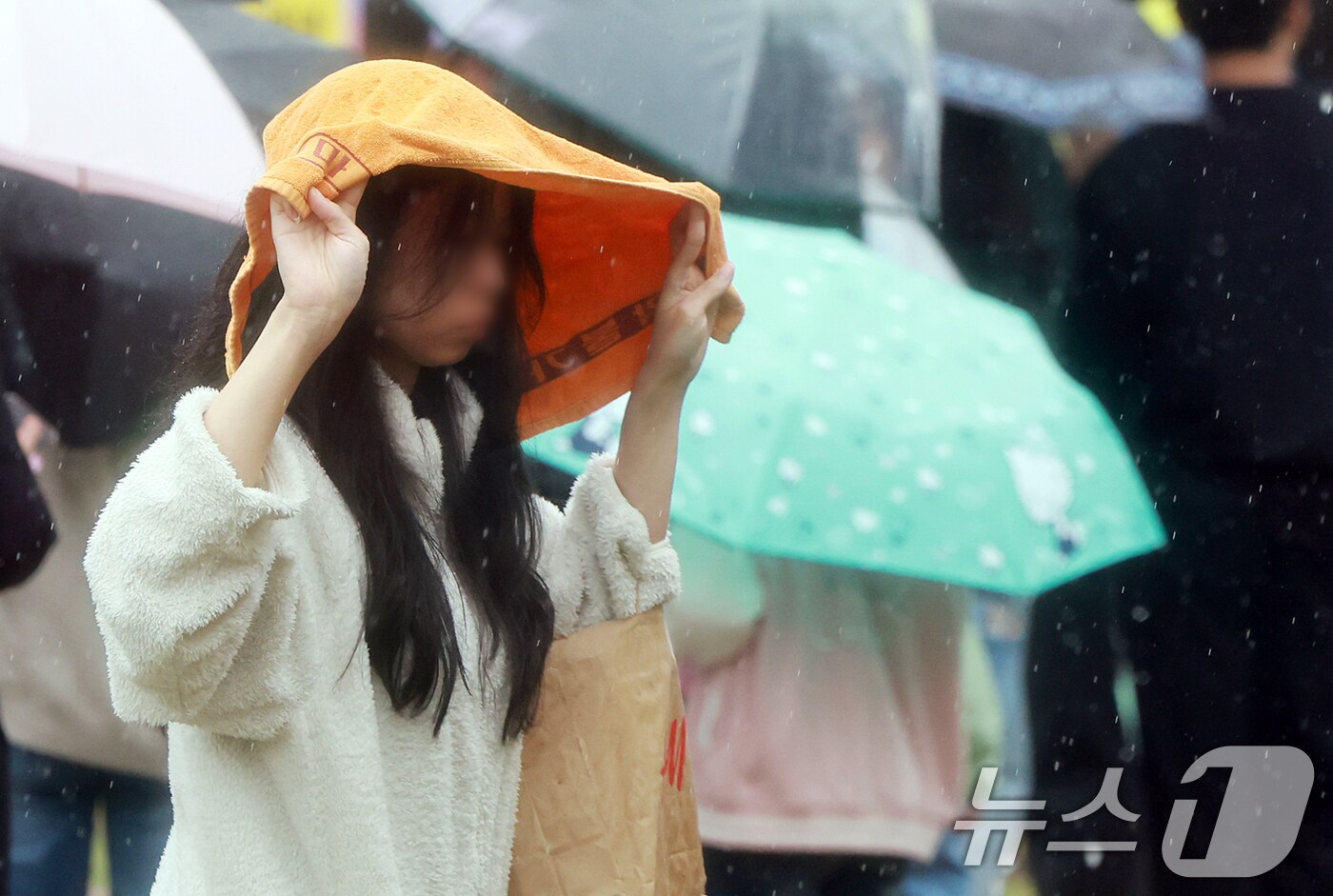 서울을 비롯한 수도권 일대에 비가 내린 1일 서울 중구 서울광장에서 한 시민들이 수건으로 비를 피하며 발걸음을 옮기고 있다. 2025.5.1/뉴스1 ⓒ News1 김진환 기자
