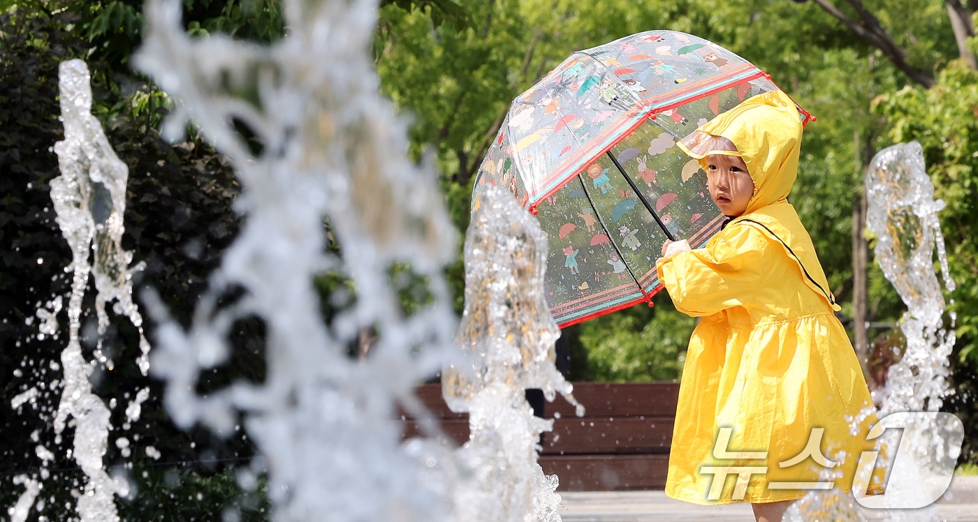 서울 종로구 광화문광장 바닥분수에서 우의를 입은 한 어린이가 물놀이를 하며 더위를 식히고 있다. 2025.5.20/뉴스1 ⓒ News1 이동해 기자