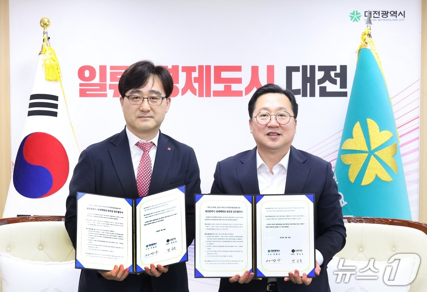  정승욱 롯데백화점 대전점장(왼쪽)과 이장우 대전시장이 28일 업무협약을 체결하고 협약서를 들어보이고 있다.(대전시 제공) /뉴스1
