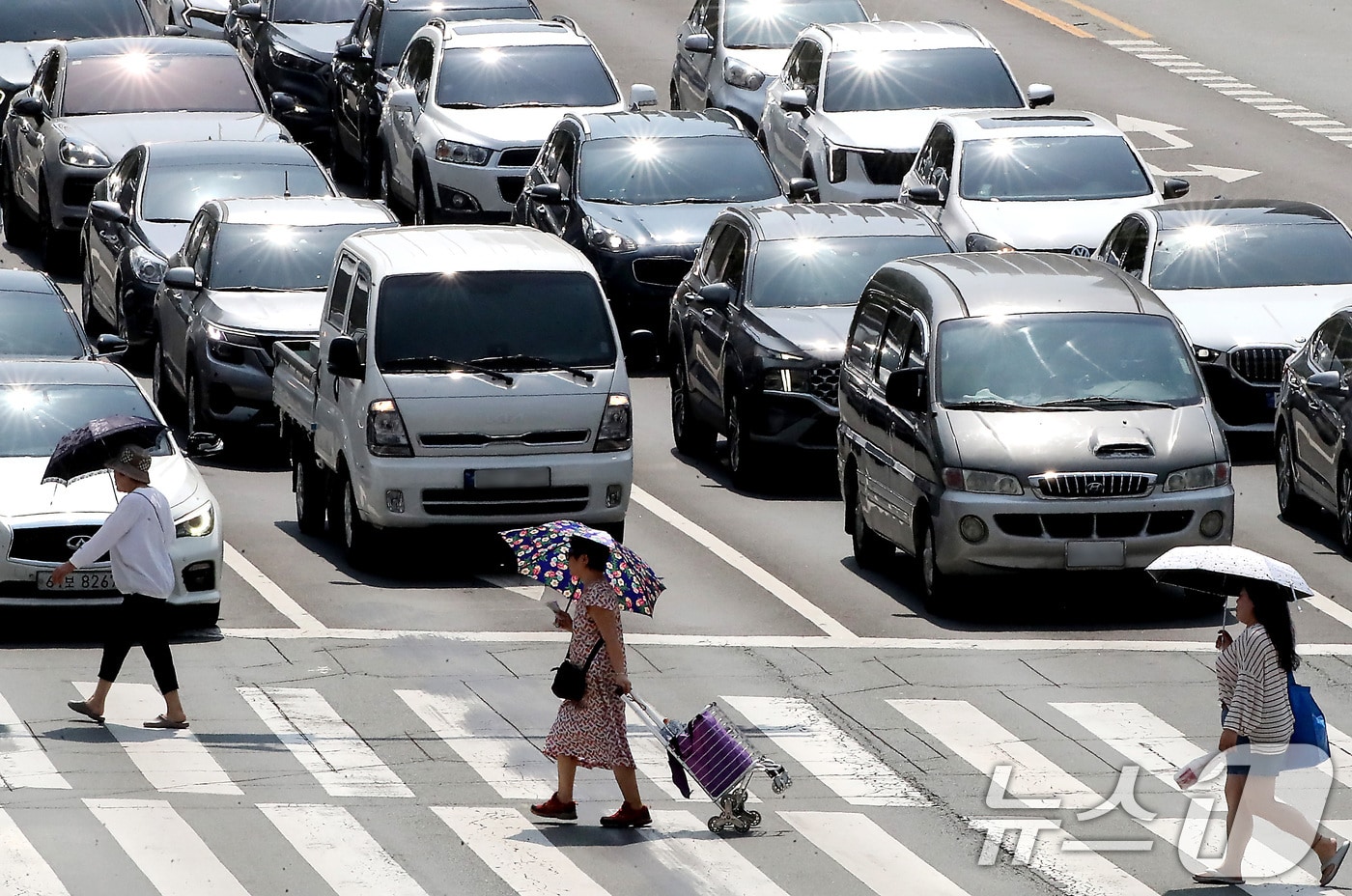 무더위가 기승을 부린 18일 오후 뜨거운 햇볕이 내리쬐는 대구 중구 달구벌대로에서 시민들이 양산을 쓴채 횡단보도를 건너고 있다. 2025.6.18/뉴스1 ⓒ News1 공정식 기자
