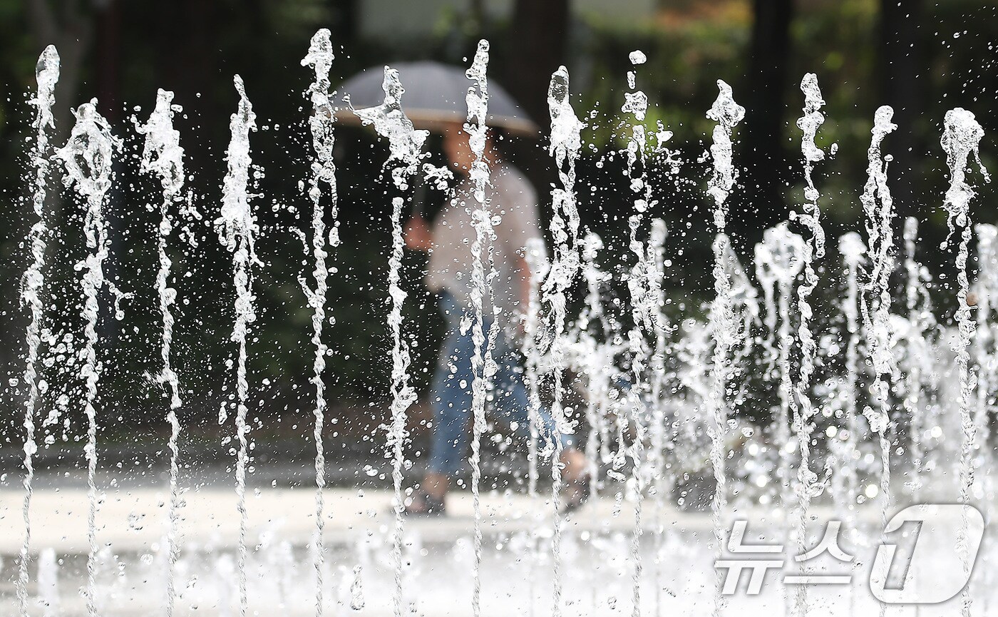 대구·경북에 올여름 첫 폭염주의보가 발효된 27일 오후 대구 서구 평리공원에서 양산을 쓴 시민이 바닥분수 옆을 지나고 있다. 2025.6.27/뉴스1 ⓒ News1 공정식 기자