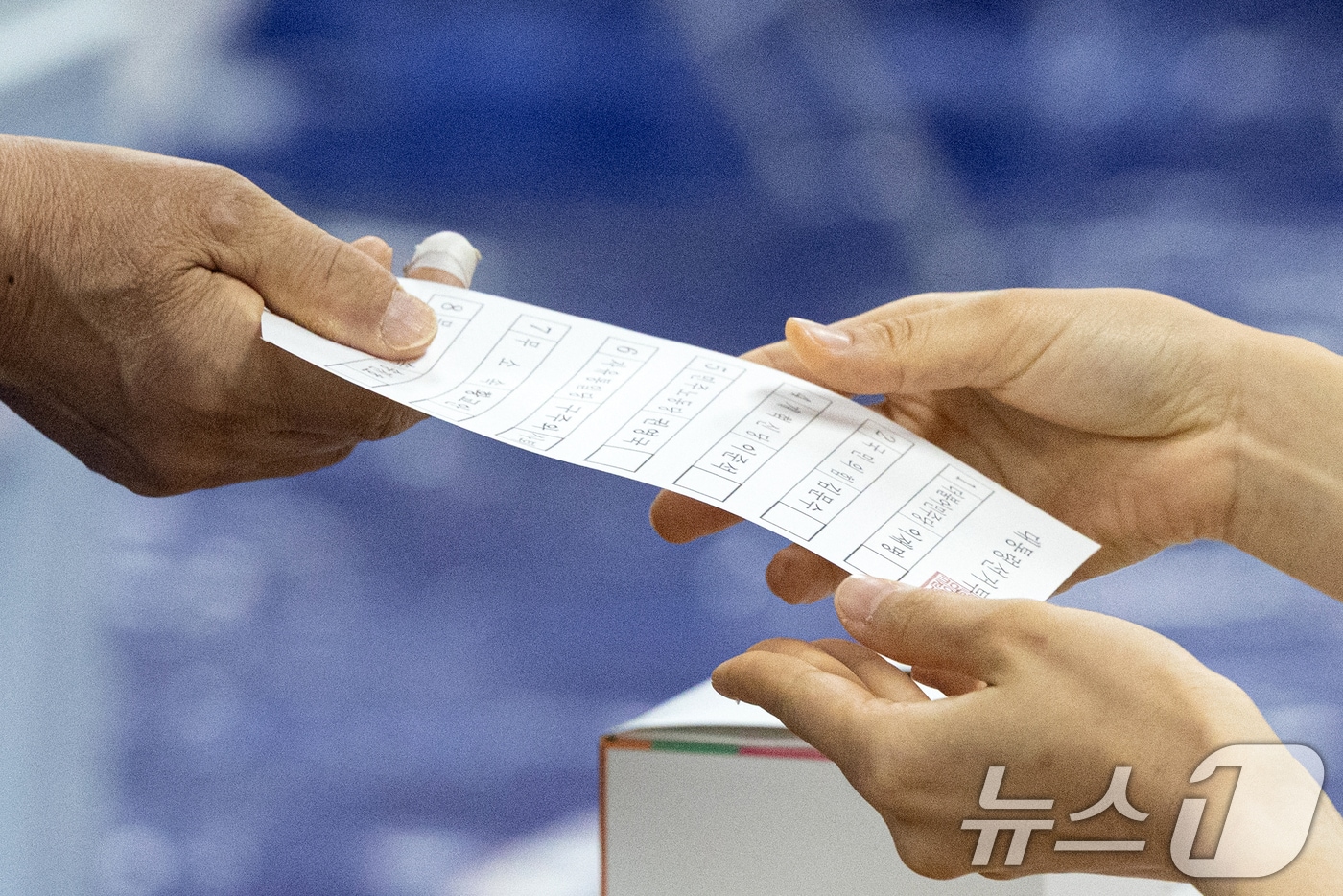 제21대 대통령 선거일인 3일 서울 영등포구 여의도 윤중중학교에 마련된 투표소를 찾은 시민이 투표용지를 받고 있다. 2025.6.3/뉴스1 ⓒ News1 이승배 기자