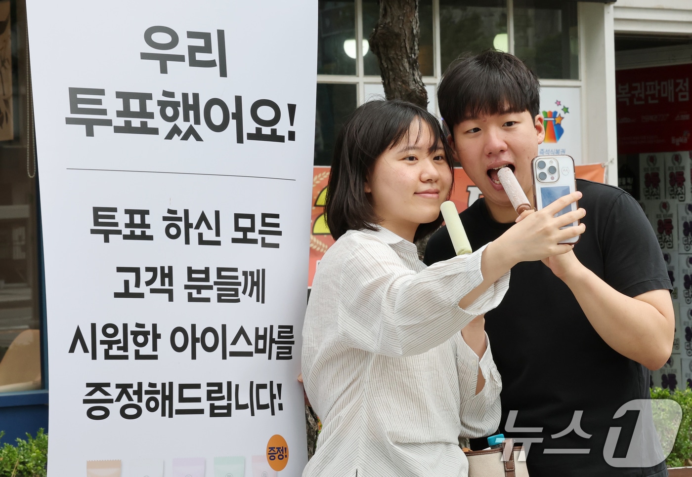 제21대 대통령 선거가 실시된 3일 대전 유성구 온천동 한 상가에서 투표한 유권자에게 아이스바를 증정하는 행사를 진행한 가운데 투표를 마친 유권자가 인증사진을 촬영하고 있다. 2025.6.3/뉴스1 ⓒ News1 김기태 기자