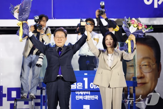  이재명 더불어민주당 대통령 후보와 부인 김혜경 여사가 4일 오전 당선이 확실시되자 서울 여의도 국회 앞을 찾아 꽃다발을 받아 들어보이고 있다. (공동취재) 2025.6.4/뉴스1 ⓒ News1 안은나 기자