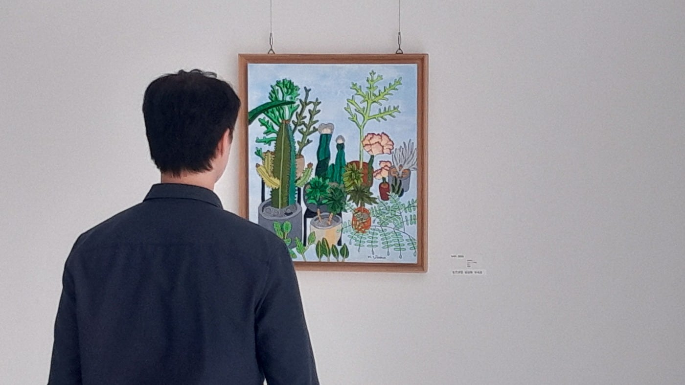  휴젤 사내에 전시된 장애예술인들의 작품을 임직원이 감상하고 있다. (휴젤 제공)