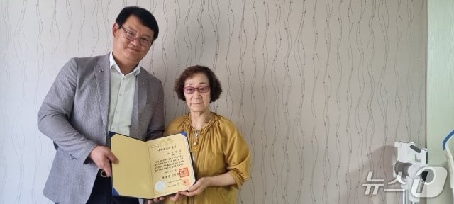  서승일 대전보훈청장과 고(故) 박광삼 무공수훈자 유족이 유공자 증서를 들어보이고 있다.(대전보훈청 제공 /뉴스1