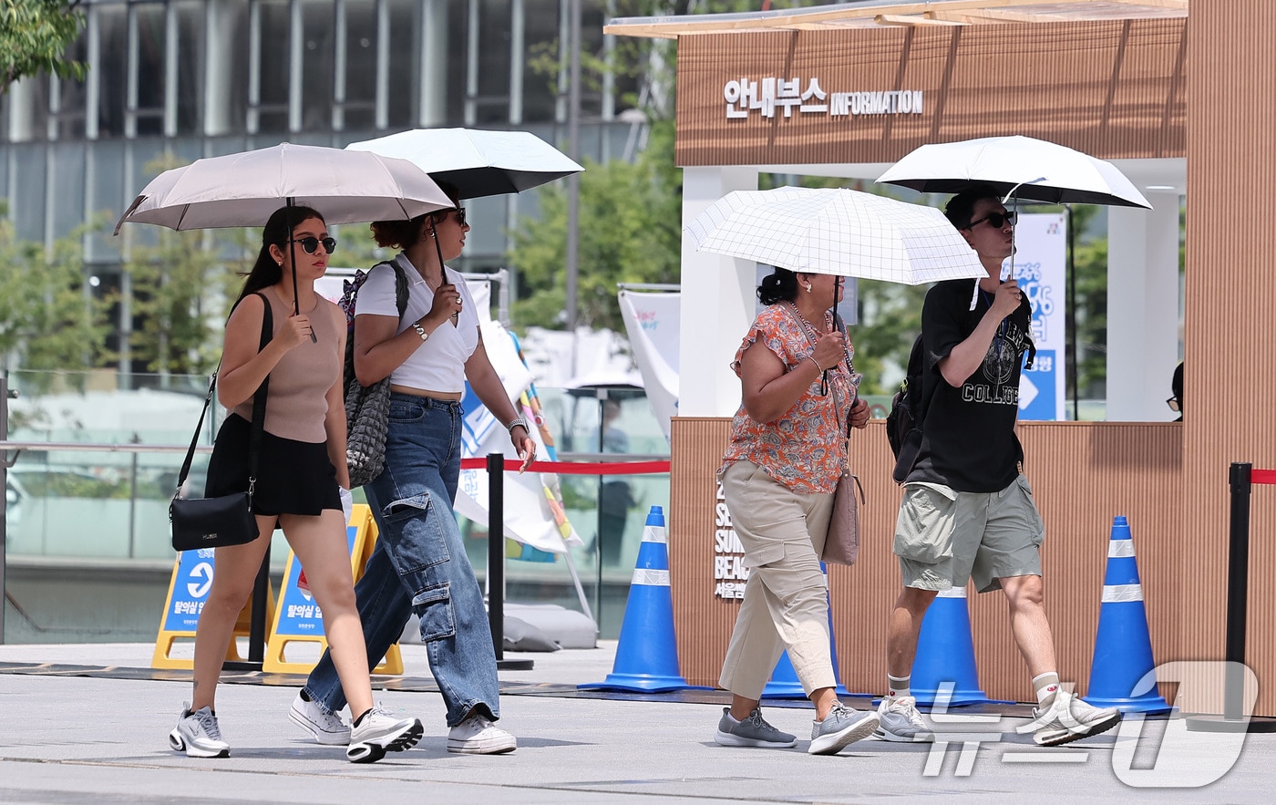 낮 최고기온이 35도까지 오르며 전국이 무더운 날씨를 보인 23일 서울 종로구 광화문광장에서 외국인 관광객들이 양산을 쓴 채 발걸음을 옮기고 있다. 2025.7.23/뉴스1 ⓒ News1 김성진 기자