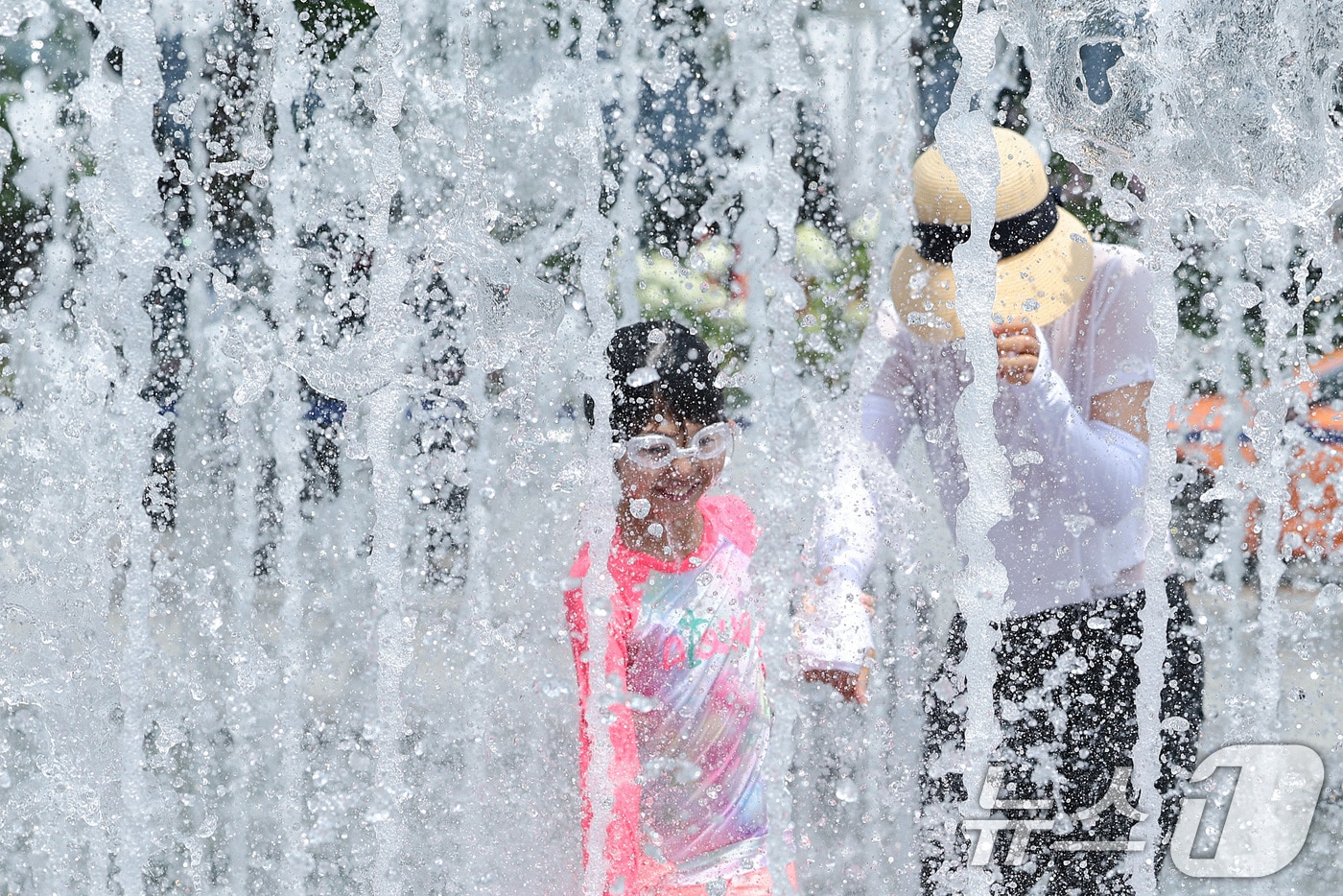 전국 대부분 지역에 폭염 경보가 발효된 25일 서울 광화문광장 바닥분수에서 한 어린이가 보호자와 함께 물놀이를 하며 더위를 식히고 있다. 기상청은 토요일인 오는 25일에는 서울 낮 최고기온이 38도까지 올라갈 것으로 예보했다. 2025.7.25/뉴스1 ⓒ News1 신웅수 기자