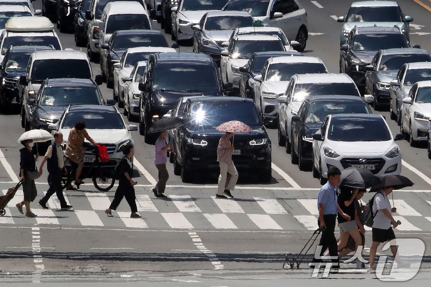 폭염이 연일 계속되는 25일 오후 대구 중구 달구벌대로에서 양산을 쓴 시민들이 아지랑이가 피어오르는 도로를 건너고 있다. 2025.7.25/뉴스1 ⓒ News1 공정식 기자