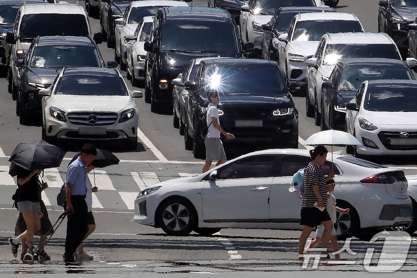 폭염특보가 발효된 대구와 경북지의 27일 오전 체감온도가 대부분 30도를 넘는 등 불볕더위가 이어지고 있다. 사진은 지난 25일 오후 대구 중구 달구벌대로에서 양산을 쓴 시민들이 아지랑이가 피어오르는 도로를 건너고 있는 모습. 2025.7.25/뉴스1 ⓒ News1 공정식 기자