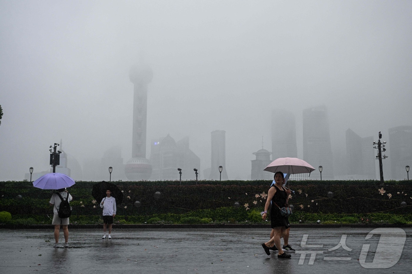 30일 제13호 태풍 ‘코메이’가 상하이를 관통하는 가운데, 황푸강 산책로를 시민들이 강풍과 폭우 속에서도 걷고 있다.2025.07.30. ⓒ AFP=뉴스1