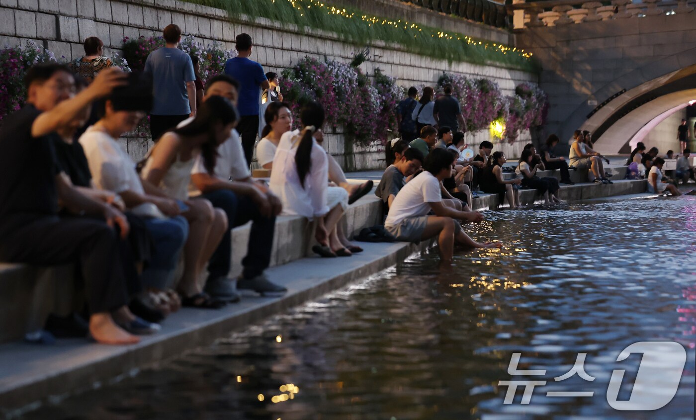 이른 폭염과 함께 열흘 넘게 열대야가 이어지고 있는 9일 저녁 서울 중구 청계천을 찾은 시민들이 더위를 식히고 있다. 2025.7.9/뉴스1 ⓒ News1 장수영 기자