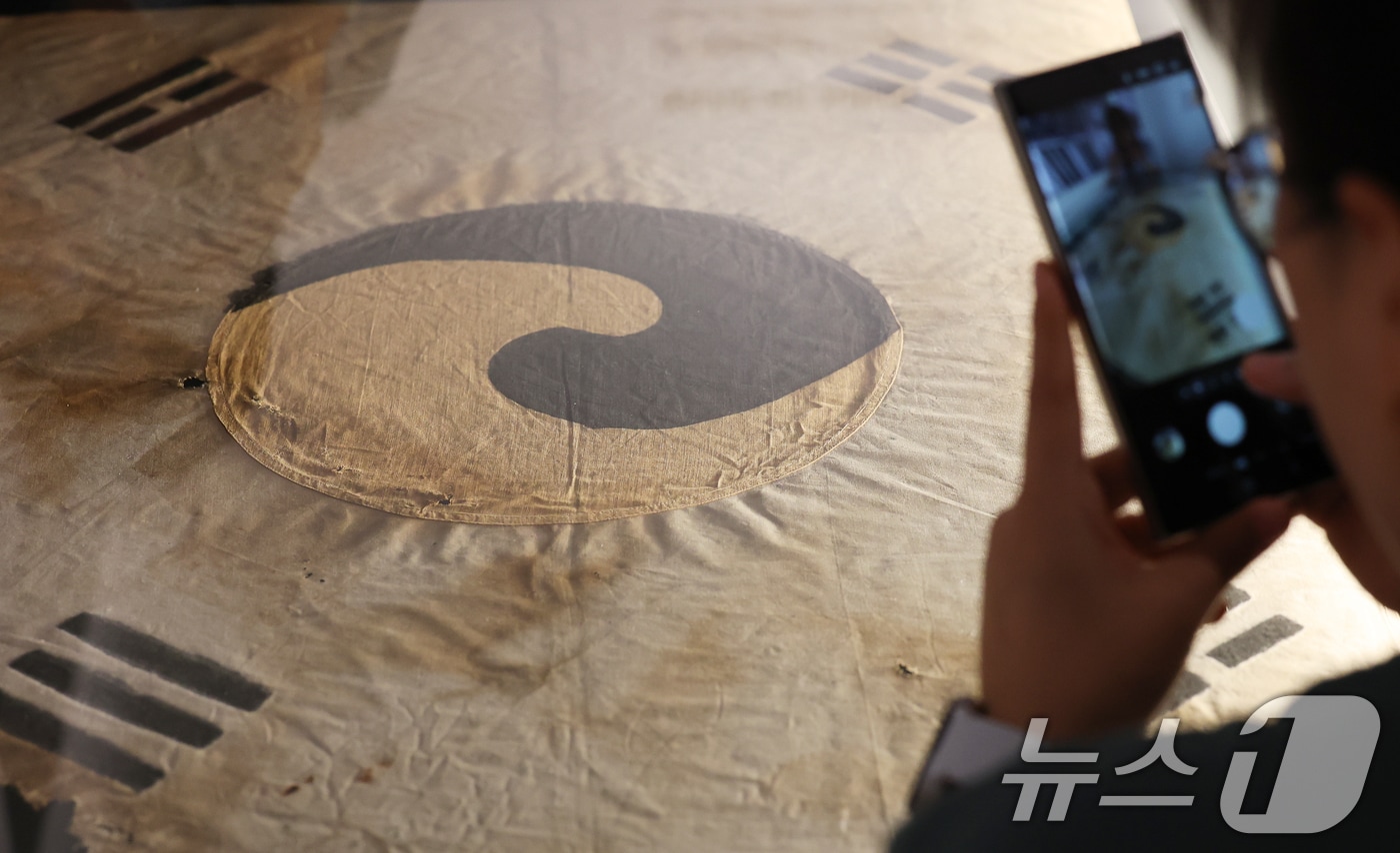 11일 오전 서울 중구 덕수궁 돈덕전에서 열린 '빛을 담은 항일유산' 특별전 언론공개회에서 방문객들이 일제강점기 당시 일장기를 먹으로 덧칠해 만든 '서울 진관사 태극기'를 살펴보고 있다. 2025.8.11/뉴스1 ⓒ News1 오대일 기자