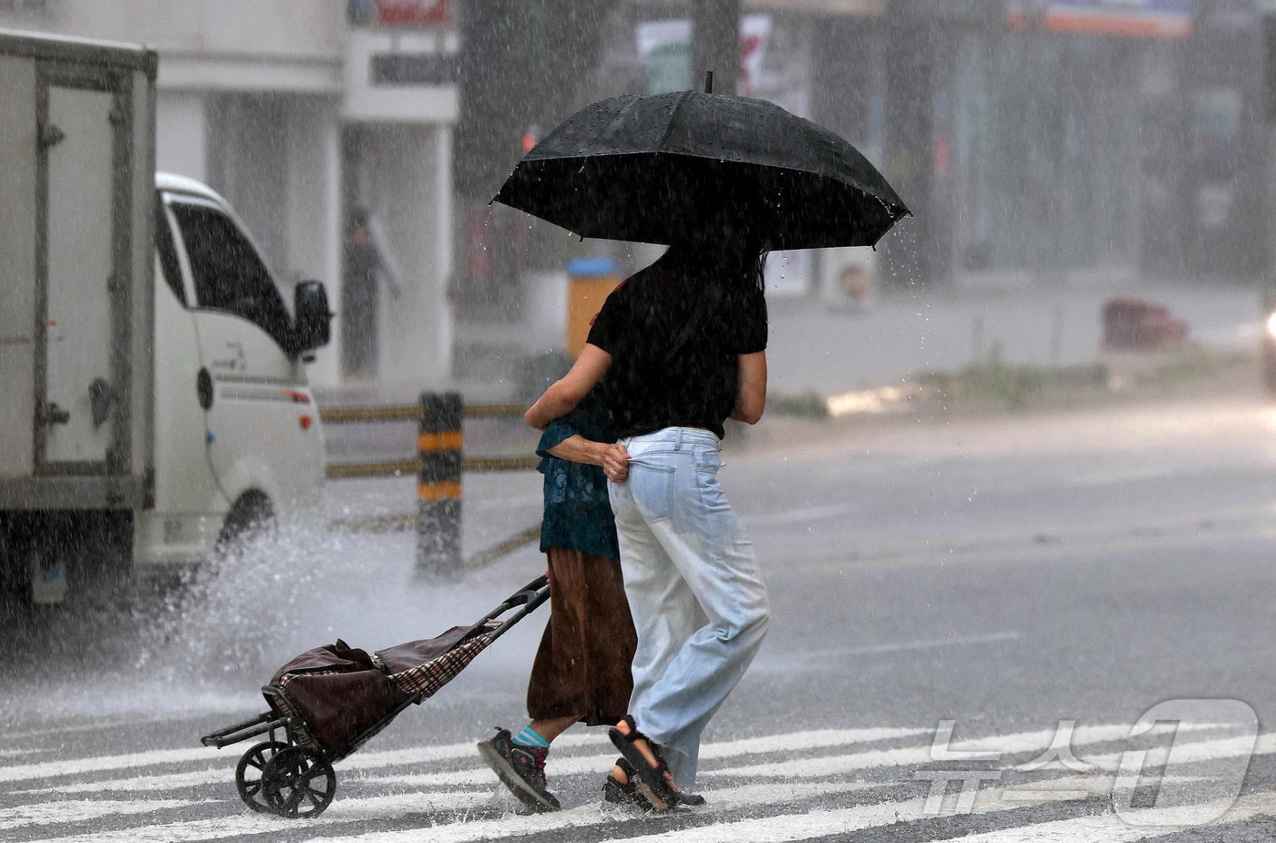 한 행인이 우산을 준비 못한 할머니 한분과 함께 우산을 같이 쓰며 횡단보도를 건너고 있다.(사진은 기사 내용과 무관함) / 뉴스1 ⓒ News1