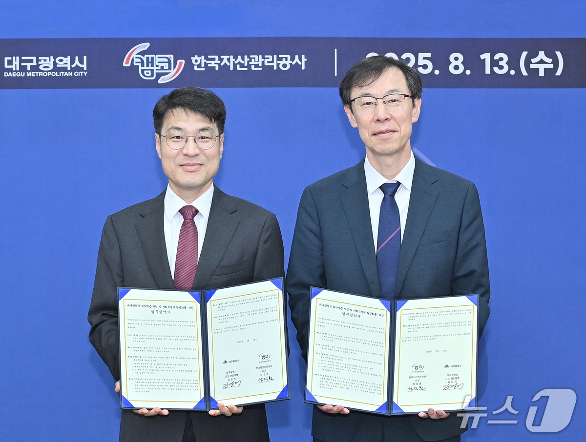 김정기 대구시장 권한대행 행정부시장&#40;완쪽&#41;과 정정훈 한국자산관리공사 사장이 금융취약계층 지원 및 사회적경제 활성화를 위한 업무협약을 체결한 후 협약서를 펼쳐 보이고 있다.&#40;대구시 제공. 재판매 및 DB 금지&#41;