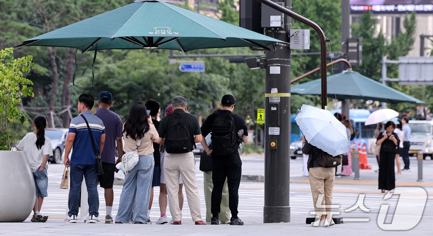 서울 광화문네거리에서 시민들이 횡단보도 앞 그늘막 아래 모여 신호를 기다리고 있다.2025.8.21/뉴스1 ⓒ News1 박지혜 기자