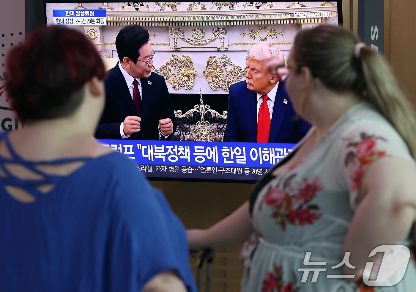 26일 오전 서울 용산구 한강대로 서울역 대합실에서 외국인들이 이재명 대통령과 도널드 트럼프 미국 대통령 간 한미 정상회담 관련 뉴스를 지켜보고 있다. 2025.8.26/뉴스1 ⓒ News1 박정호 기자
