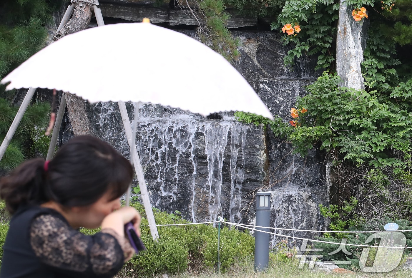 폭염이 계속된 28일 오후 대구 북구의 한 아파트 단지에서 양산을 쓴 시민이 인공폭포 앞을 지나고 있다. 2025.8.28/뉴스1 ⓒ News1 공정식 기자