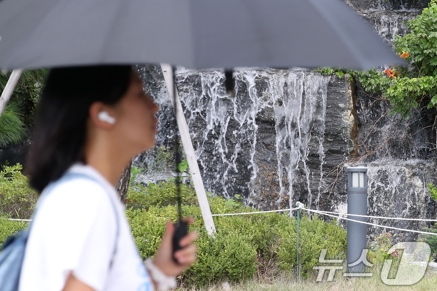 폭염이 계속된 28일 오후 대구 북구의 한 아파트 단지에서 양산을 쓴 시민이 인공폭포 앞을 지나고 있다. 2025.8.28/뉴스1 ⓒ News1 공정식 기자