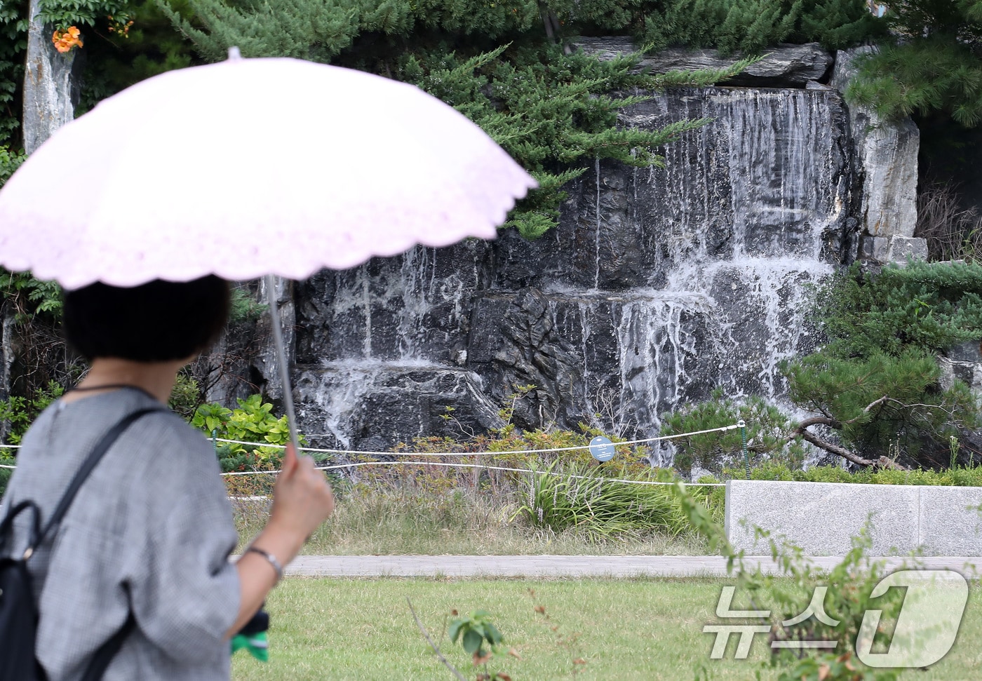 폭염이 계속된 28일 오후 대구 북구의 한 아파트 단지에서 양산을 쓴 시민이 인공폭포 앞을 지나고 있다. 2025.8.28/뉴스1 ⓒ News1 공정식 기자