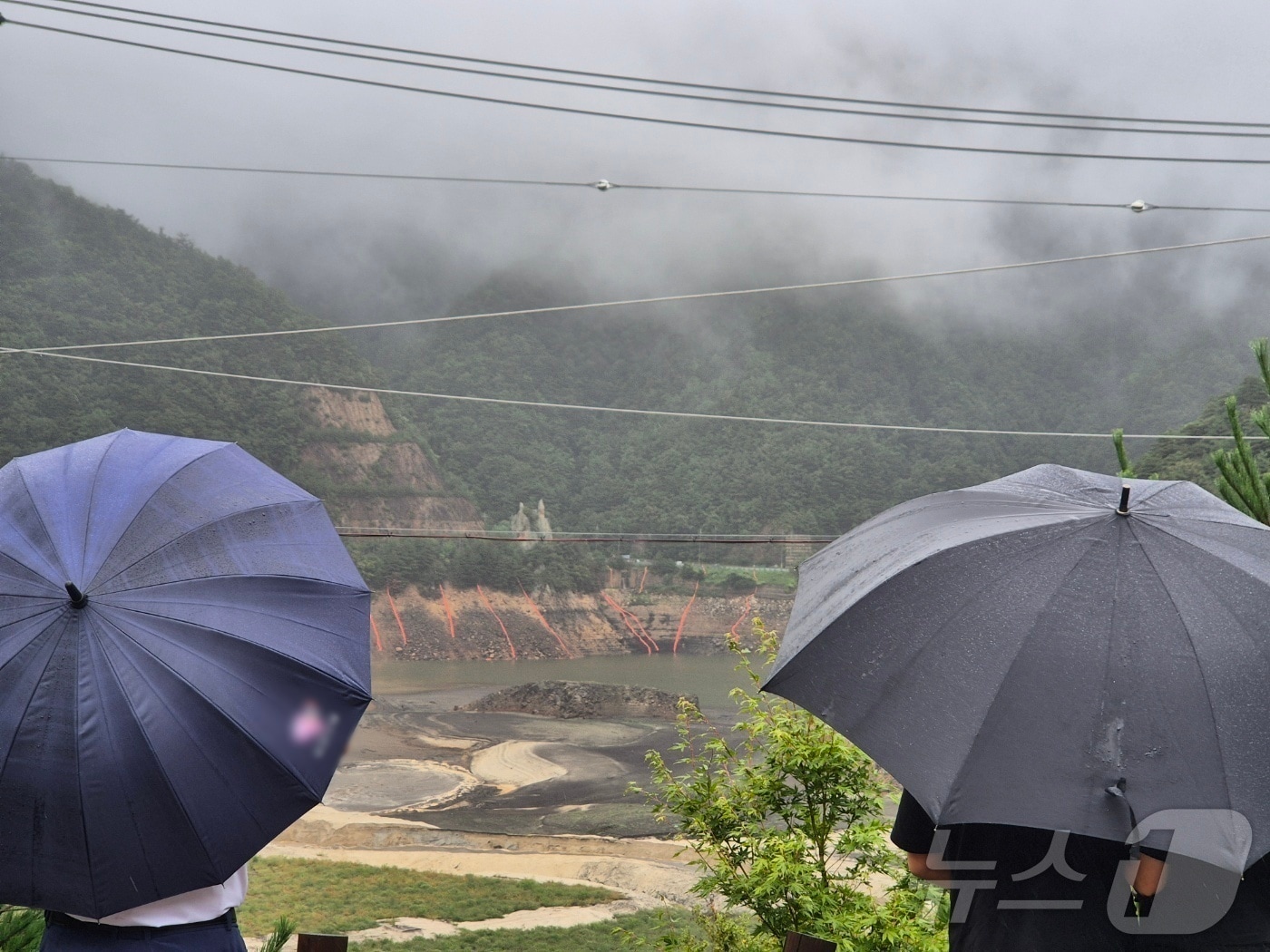 우산을 쓴 시민이 마른 저수지에 내리는 단비를 바라보고 있다. (뉴스1 DB)ⓒ News1 윤왕근 기자