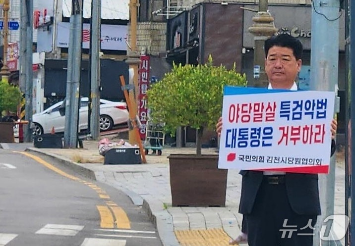 나영민 김천시의장이 지난 15일 김천지역 거리에서 '야당 말살 특검 악법 대통령은 거부하라'는 손팻말을 들고 1인 시위를 벌이고 있다. (나영민 시의장 페이스북 갈무리/뉴스1)