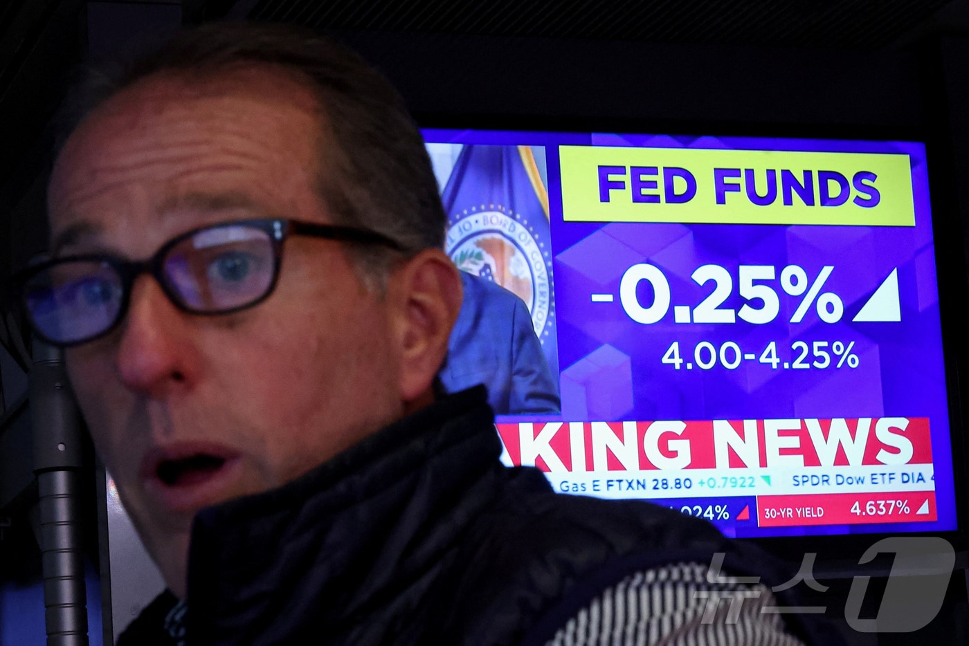 미증시의 한 트레이더. 화면에 0.25%포인트 금리 인하 소식이 나오고 있다. ⓒ 로이터=뉴스1