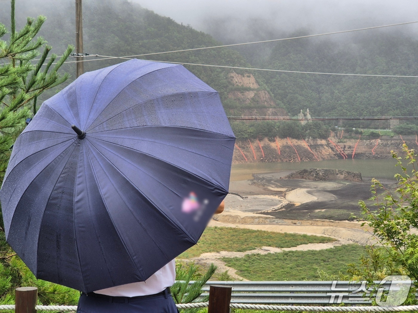 우산을 쓴 시민이 오봉저수지에 내리는 단비를 바라보고 있다. (뉴스1 DB)ⓒ News1 윤왕근 기자