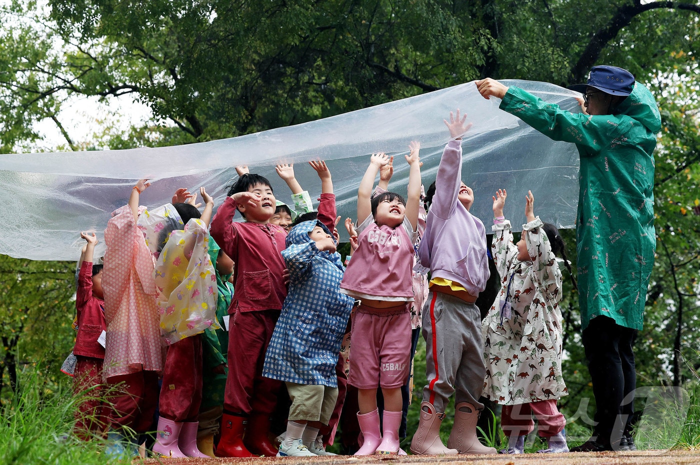 비가 내린 지난 25일 광주 북구 문흥동 문화근린공원 유아숲체험원에서 열린 숲체험 프로그램에 참가한 매곡어린이집 아이들이 숲해설사와 비닐에 떨어지는 빗소리를 들으며 자연을 느끼고 있다.&#40;광주 북구 제공. 재판매 및 DB 금지&#41; 2025.9.25/뉴스1 