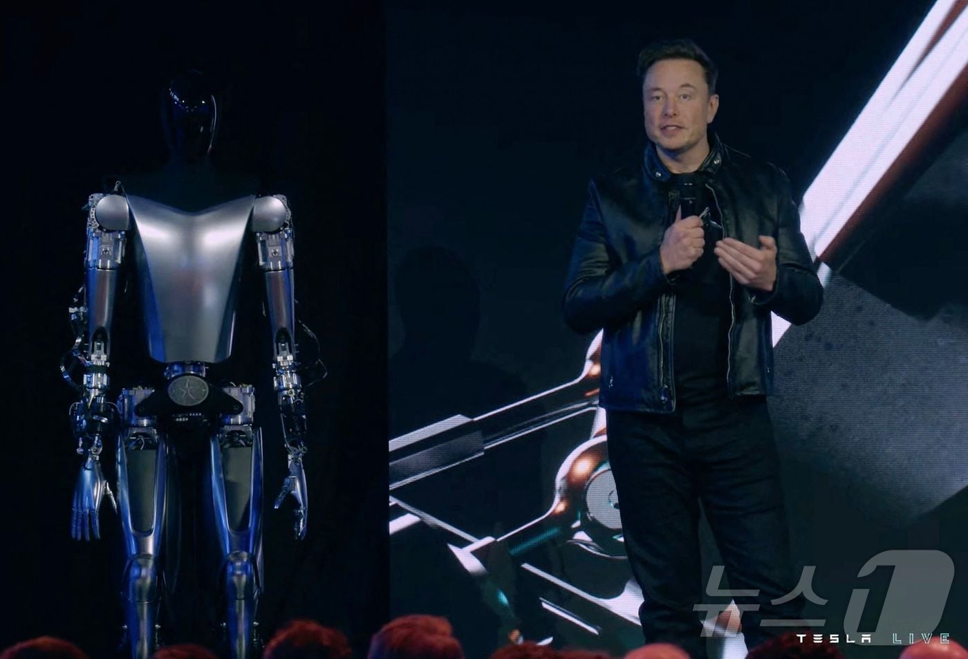 2022년 9월 30일, 미국 캘리포니아주 팰로앨토에서 열린 ‘테슬라 AI 데이 2022’ 생중계 영상 화면 캡처. 일론 머스크 테슬라 최고경영자가 휴머노이드 로봇 옵티머스 옆 무대에 서 있는 모습이 담겼다.2022.09.30.ⓒ AFP=뉴스1
