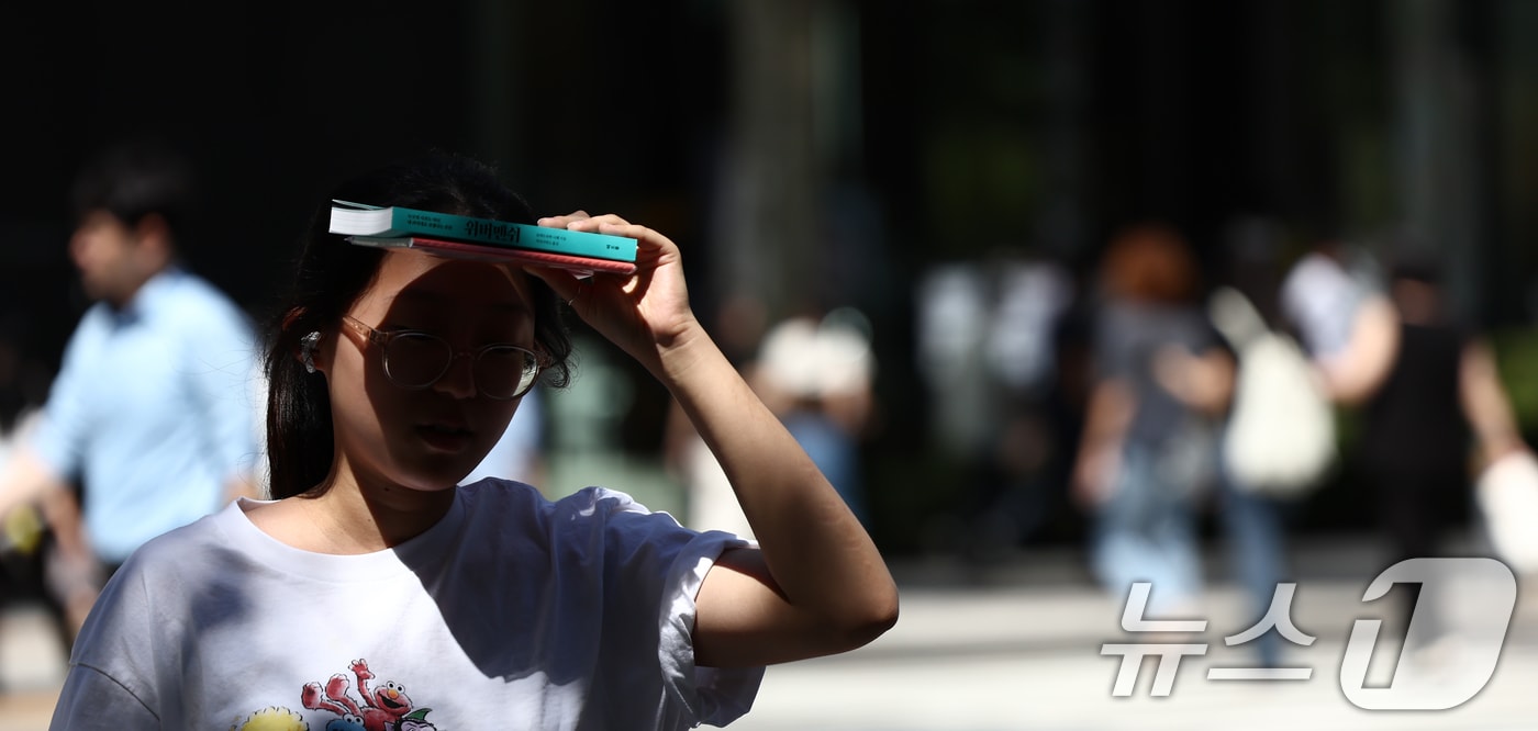 서울 낮 기온이 30도 이상 오르며 푹푹 찌는 무더위가 이어진 5일 오후 서울 종로구 일대에서 시민이 책으로 햇볕을 가리며 발걸음을 옮기고 있다. 2025.9.5/뉴스1 ⓒ News1 김민지 기자