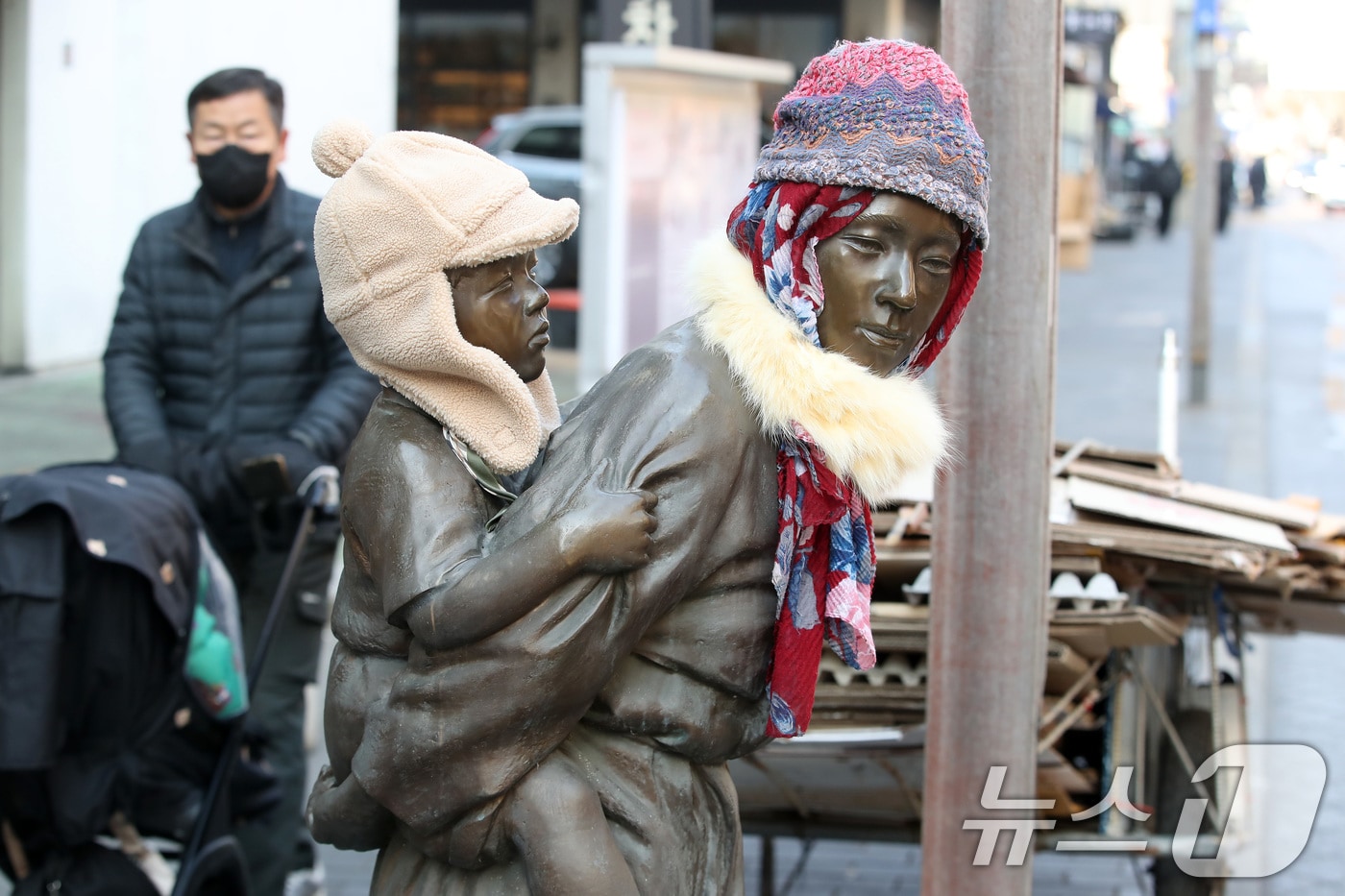 동장군이 기승을 부린 23일 오후 대구 중구 종로 약령시 인근에 세워진 '엄마의 마음' 조각상(이현우 작)에 시민들이 씌워놓은 방한모와 목도리가 눈길을 끌고 있다. 이 조각은 김원일의 소설 '마당 깊은 집' 주인공 길남엄마가 막내 길수를 업고 신문 배달 나간 길남이를 기다리는 모습을 형상화한 작품이다. 2026.1.23/뉴스1 ⓒ News1 공정식 기자