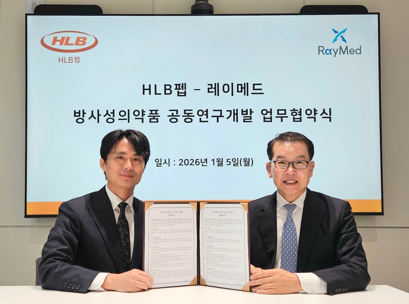  심경재 HLB펩 대표이사(사진 왼쪽)와 김영현 레이메드 대표이사가 '방사성의약품 공동연구개발 업무협약'을 체결하고 기념 촬영을 하고 있다. (HLB펩 제공)
