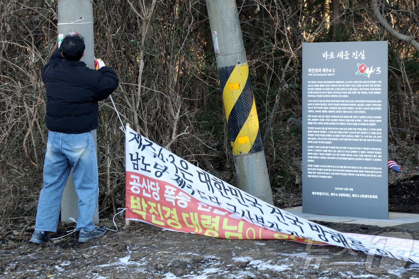 제주시 연동 주민센터 공무원이 9일 오후 제주시 연동 4·3 역사 왜곡 대응 안내판 '바로 세운 진실' 앞에 설치된 4·3 역사 왜곡 현수막을 강제 철거하고 있다. 2026.1.9/뉴스1 ⓒ News1 오미란 기자