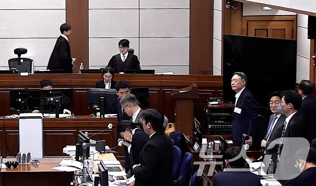서울중앙지법 형사 25부 재판장인 지귀연 부장판사가  지난 9일  내란 우두머리 혐의 1심 결심 공판 때 휴정을 선언한 뒤 자리에서 일어나자 윤석열 전 대통령도 자리를 뜨려 하고 있다. 9일 결심공판은 김용현 전 국방부 장관 측 변호인들이 서증조사에 10시간 30분을 소비하는 바람에 오는 13일로 결심공판 기일이 추가로 지정됐다.  (서울중앙지방법원 제공 영상 캡쳐. 재판매 및 DB 금지) 2026.1.9/뉴스1