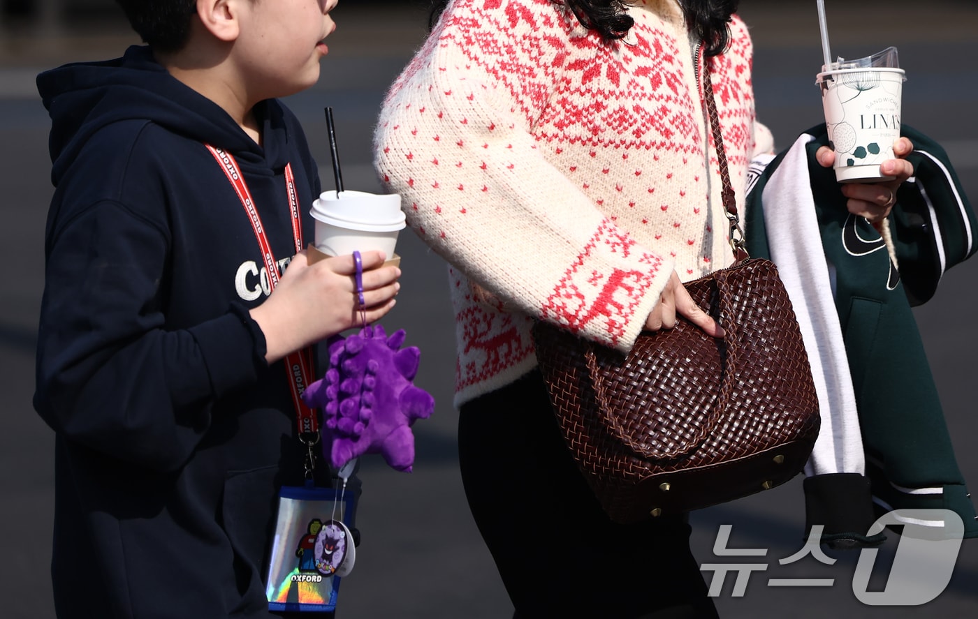 서울 광화문 사거리에서 시민이 외투를 들고 발걸음을 옮기고 있다. 2026.2.20 ⓒ 뉴스1 김민지 기자