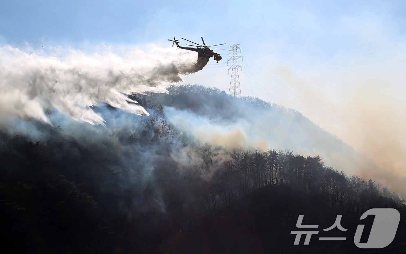 8일 오전 경북 경주시 문무대왕면 산불이 강풍을 타고 주변으로 확산하는 가운데 산불 진화에 투입된 헬기가 송전탑 주변을 날아가며 산불을 진화하고 있다. 2026.2.8 ⓒ 뉴스1 공정식 기자