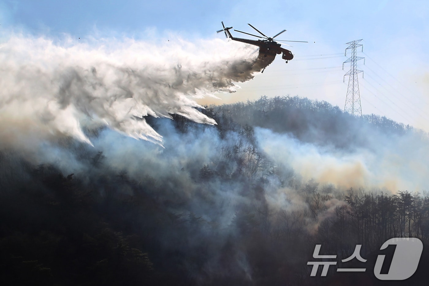 8일 오전 경북 경주시 문무대왕면 산불이 강풍을 타고 주변으로 확산하는 가운데 산불 진화에 투입된 헬기가 송전탑 주변을 날아가며 산불을 진화하고 있다. 2026.2.8 ⓒ 뉴스1 공정식 기자