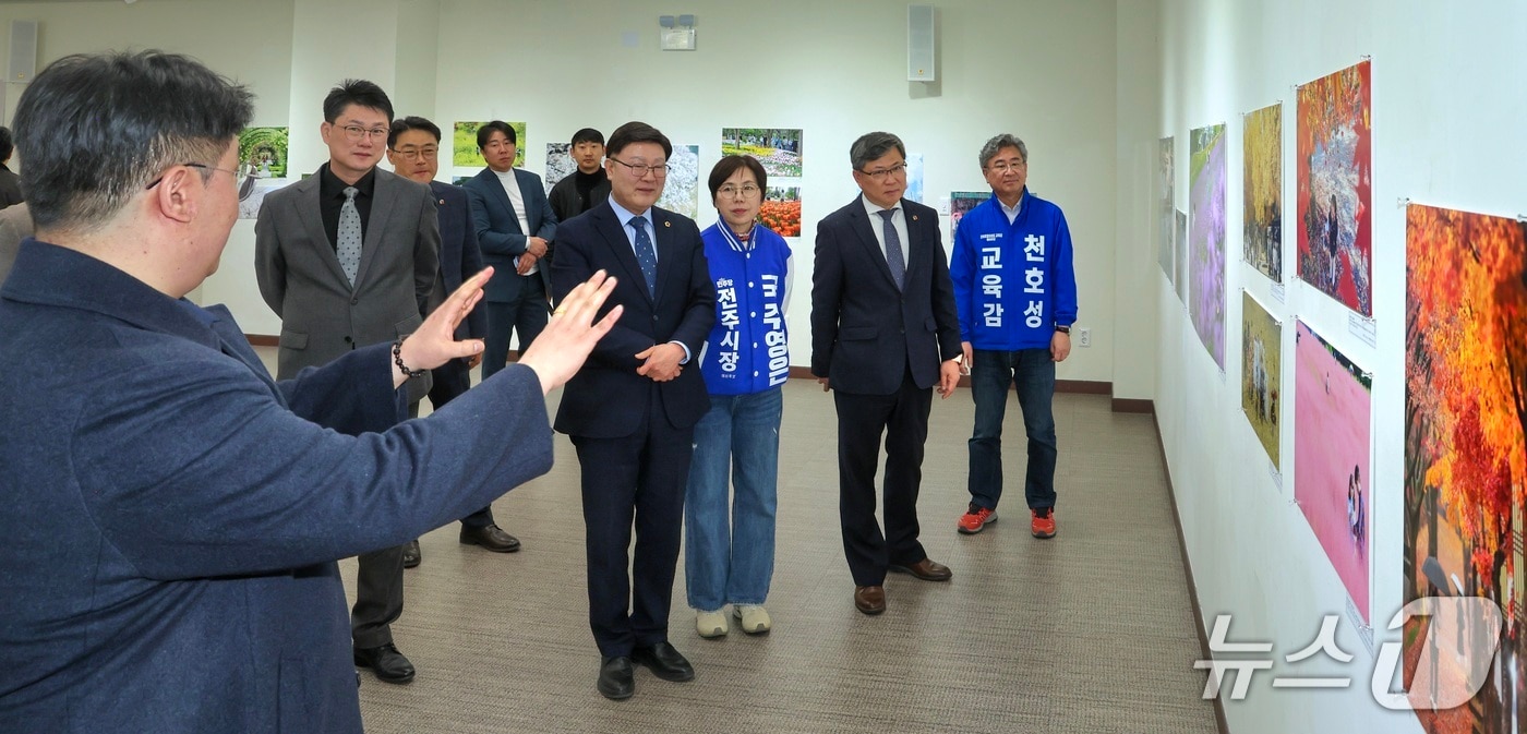 김얼(왼쪽) 전북사진기자협회 협회장이 23일 전북 전주시 전북대학교 JBNU컨벤션센터 전시실에서 열린 '2026 전북보도사진전'에서 내빈들과 함께 전시 라운딩을 하고 있다.(전북사진기자협회 제공. 재판매 및 DB금지)