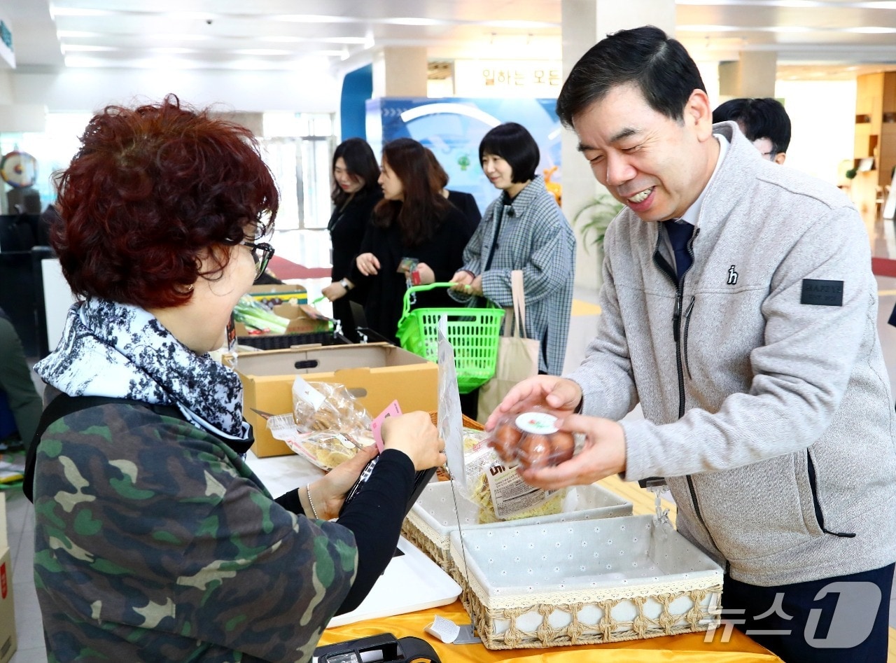 박종길 근로복지공단 이사장(오른쪽)이 24일 공단 울산본부 1층 로비에서 열린 상생마켓에 방문해 물건을 구매하고 있다. (근로복지공단 제공. 재판매 및 DB 금지) /뉴스1