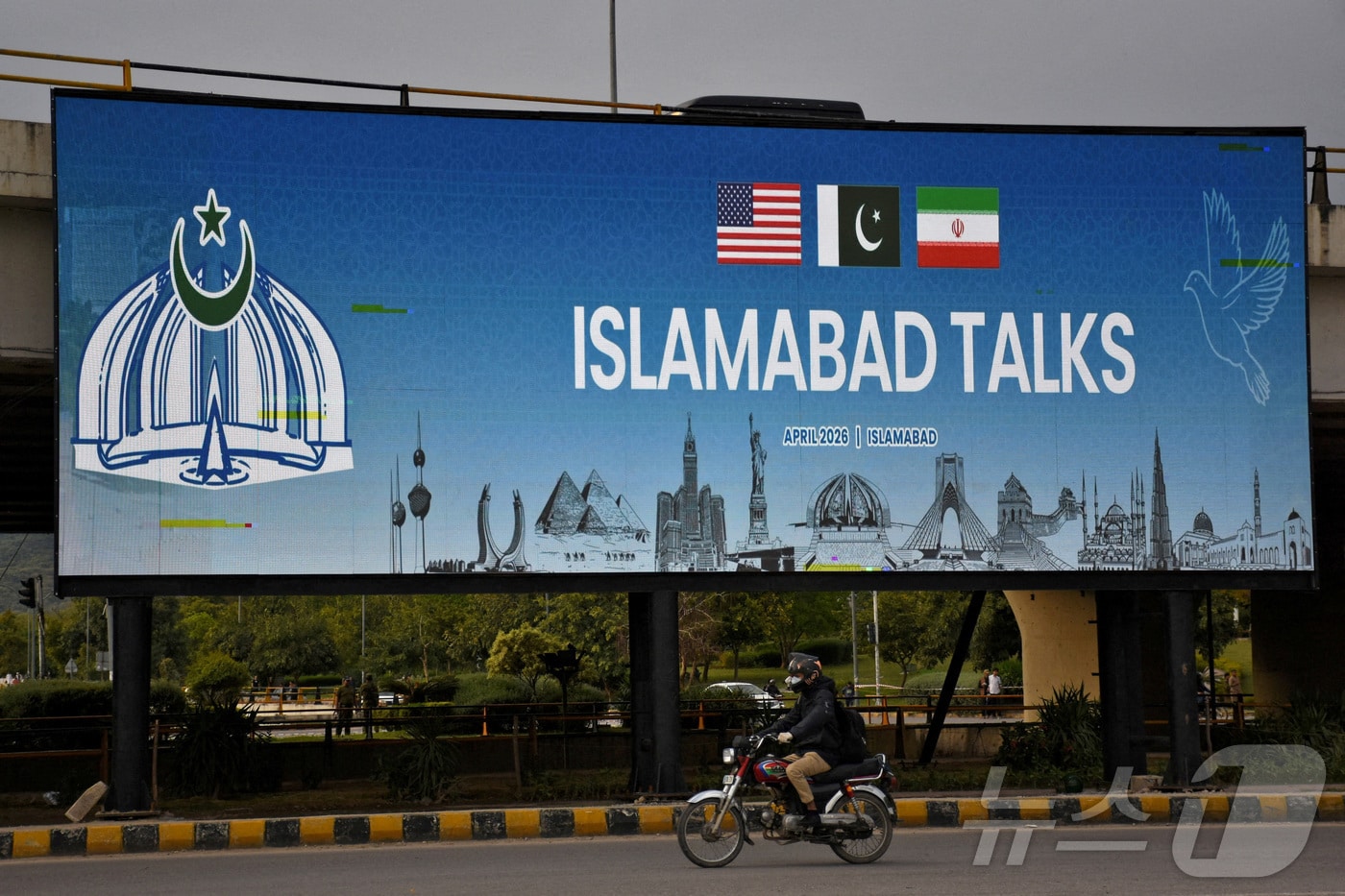 파키스탄이 미국과 이란의 평화 회담 개최를 준비하는 가운데 10일 파키스탄 이슬라마바드에서 한 남성이 도로변에 설치된 광고판 앞을 오토바이를 타고 지나가고 있다. 2026.4.10 ⓒ 로이터=뉴스1