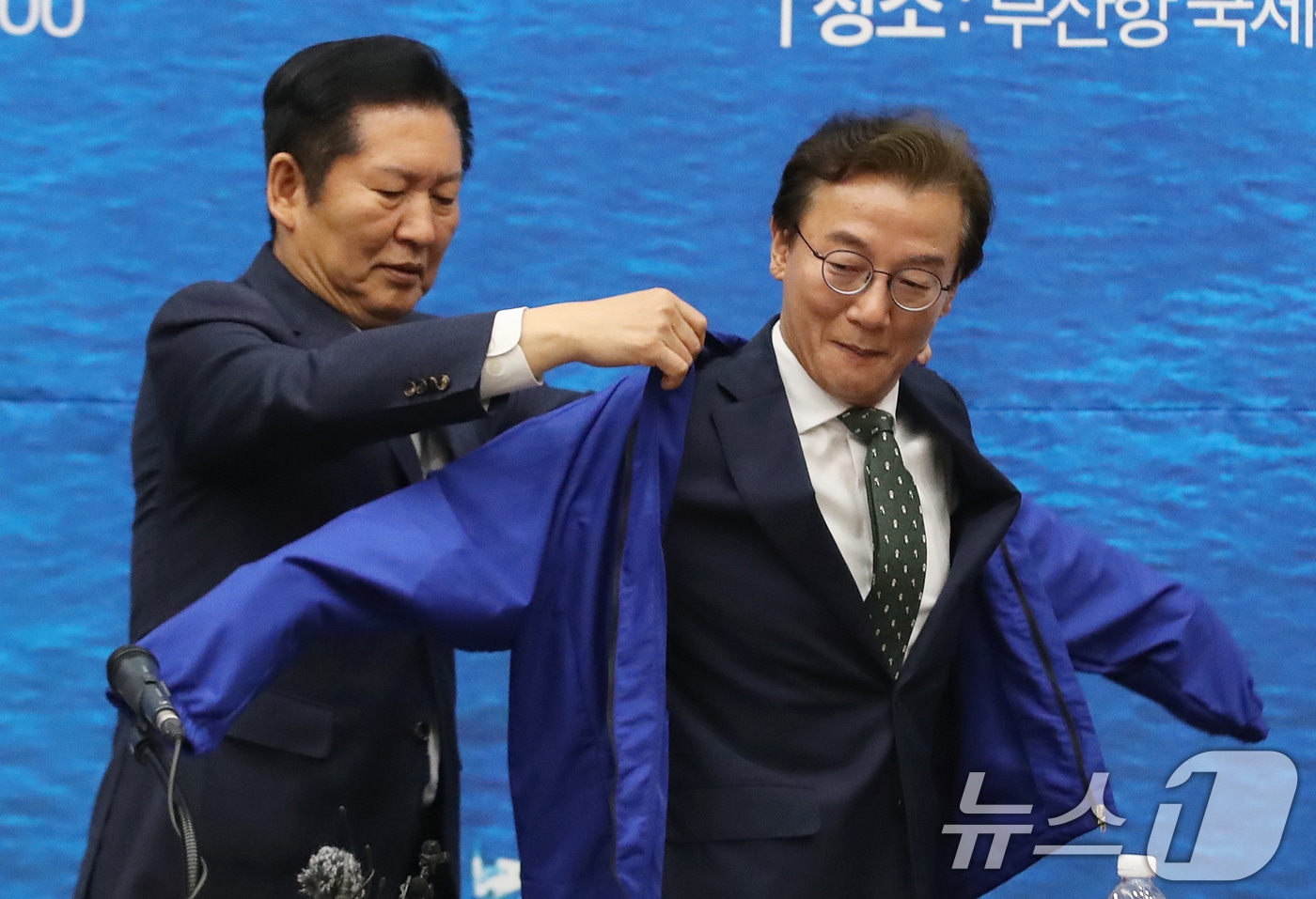 정청래 더불어민주당 대표가 15일 부산 동구 부산항국제전시컨벤션센터에서 열린 부산 현장 최고위원회의에서 전재수 부산시장 후보에게 당 점퍼를 입혀주고 있다. 2026.4.15 ⓒ 뉴스1 윤일지 기자