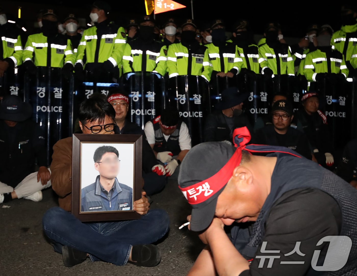 20일 경남 진주시 정촌면 CU 진주물류센터 앞에서 화물연대 노조원이 집회 중 2.5톤 화물차에 치어 숨진 노조원의 영정을 들고 슬픔에 잠겨 있다. 이날 현장에서는 화물차와 집회 참가자 3명이 충돌해 1명이 숨지고 2명이 다치는 사고가 발생했다. 2026.4.20 ⓒ 뉴스1 윤일지 기자