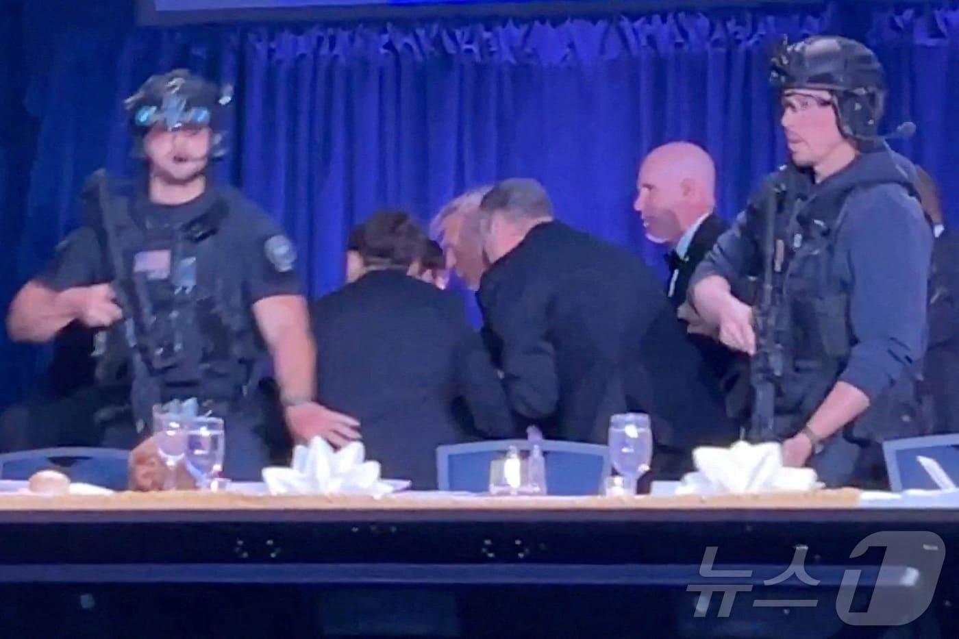 도널드 트럼프 미국 대통령이 25일(현지시간) 워싱턴 DC의 워싱턴 힐튼호텔에서 열린 백악관 기자단 만찬 행사에서 총격소리가 나자 경호를 받으며 대피하고 있다. 트럼프 대통령은 무사 피신했으며 용의자는 체포 된것으로 알려졌다. ⓒ 로이터=뉴스1