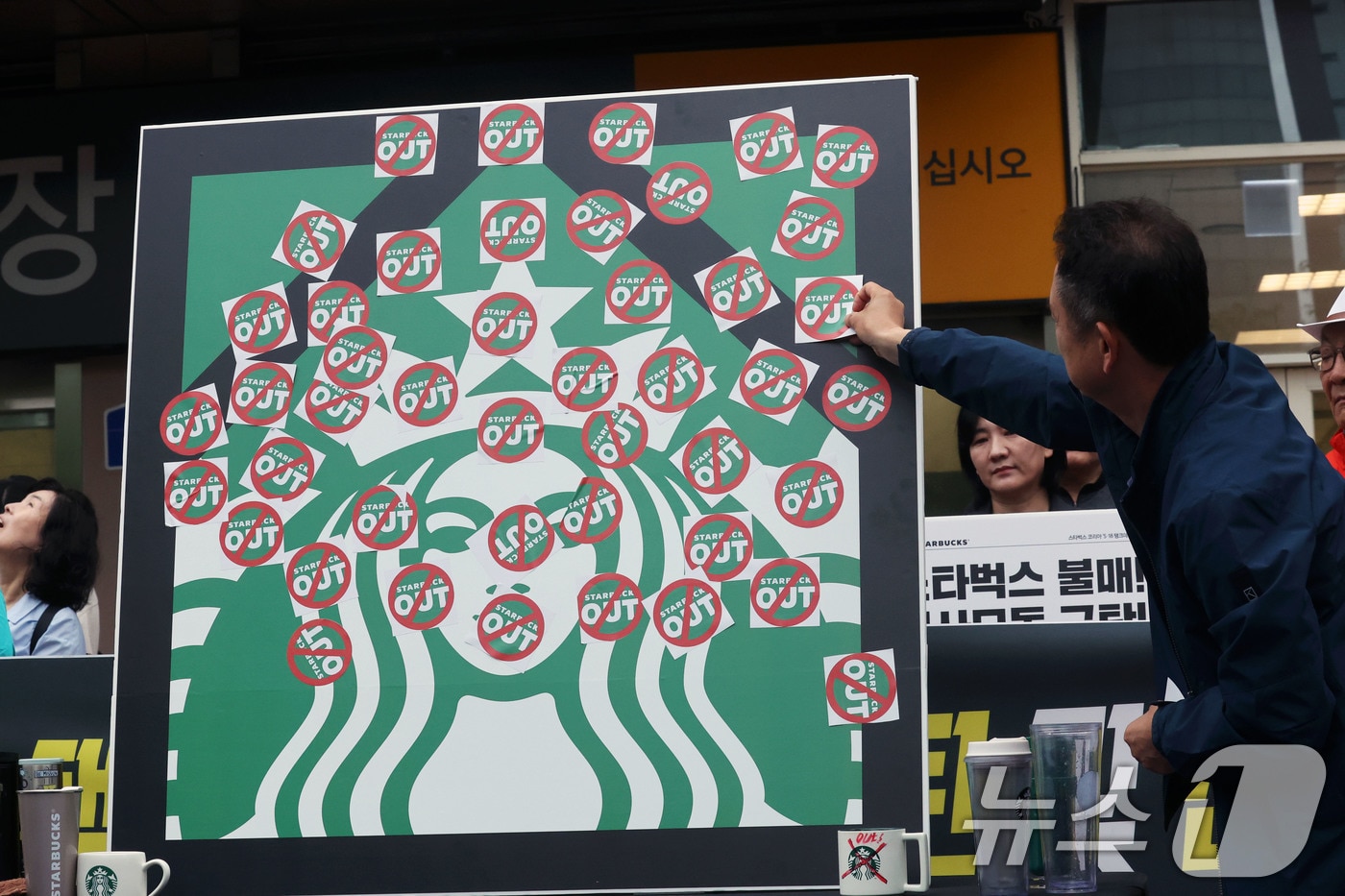 오월을 사랑하는 모임 등 광주시민단체 들이 21일 오후 광주 서구 광천동 이마트 광주점 앞에서 스타벅스의 '5·18 탱크데이' 마케팅을 규탄하는 기자회견을 열고 스타벅스 OUT 스티커를 붙이고 있다. 2026.5.21 ⓒ 뉴스1 조수민 수습기자