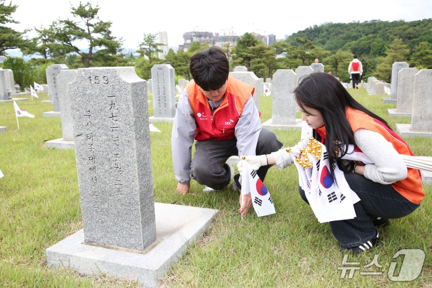 SKC 구성원들이 21일 오후 국립서울현충원 묘비 앞에 태극기를 꽂으며 묘역 정화 활동을 진행하고 있다(SKC 제공). 2026.5.21.
