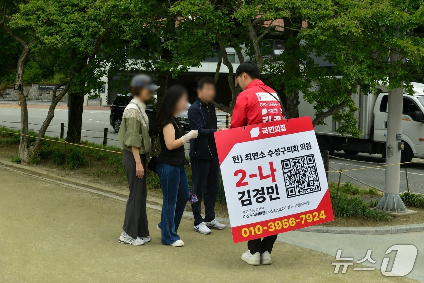 22일 오전 대구 수성구 수성못에서 김경민 국민의힘 수성구의원(마선거구) 후보가 QR코드와 자신의 휴대전화 번호가 담긴 홍보물을 착용한 채 시민들에게 인사하며 선거운동을 하고 있다.2026.5.22 ⓒ 뉴스1 이성덕 기자