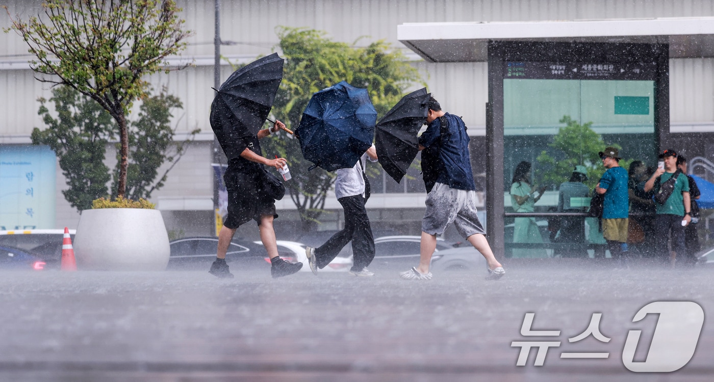 돌풍과 벼락을 동반한 소나기가 내린 14일 서울 종로구 광화문광장에서 시민들이 우산을 쓰고 발걸음을 옮기고 있다. 2026.6.14 ⓒ 뉴스1 이호윤 기자