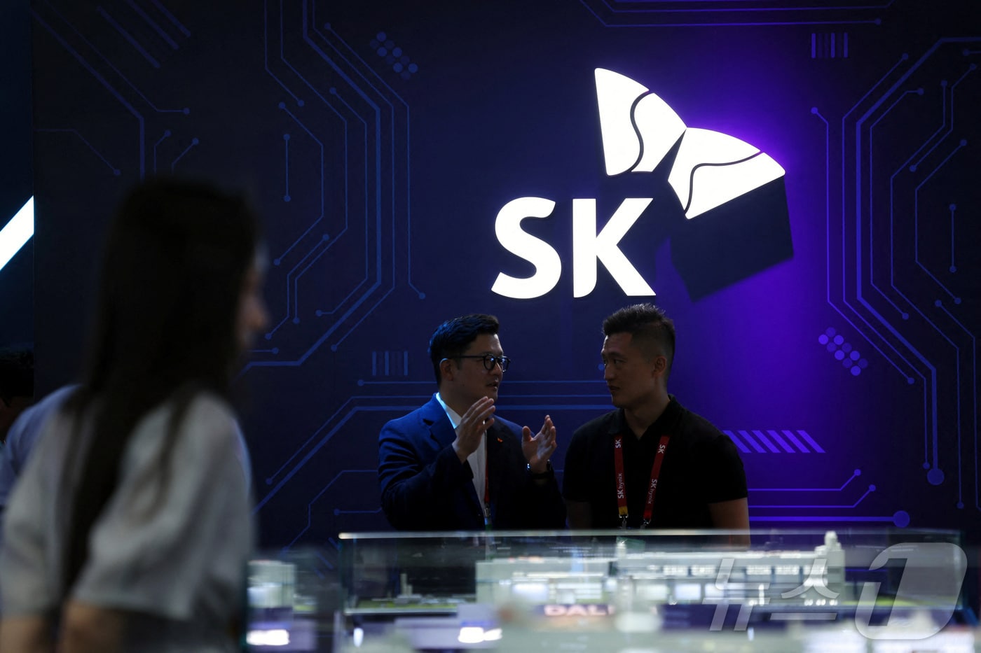 People stand near a logo of SK Hynix at the South Korean chipmaker's booth during the China International Supply Chain Expo (CISCE) in Beijing, China June 22, 2026. REUTERS/Florence Lo ⓒ 로이터=뉴스1